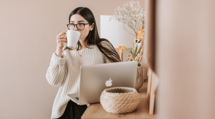 A woman drinking coffee and looking at the computer.