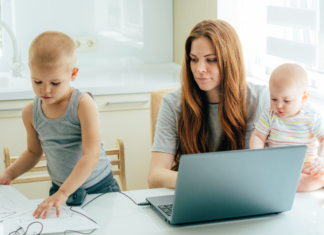 A mom with two toddlers trying to work on her computer.