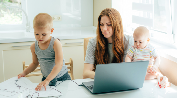 A mom with two toddlers trying to work on her computer.