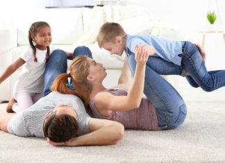 A family laying on the floor playing.