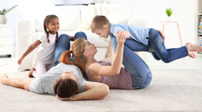 A family laying on the floor playing.