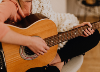 A woman sitting and playing the guitar.