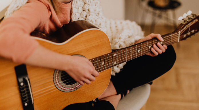 A woman sitting and playing the guitar.