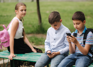 A girl looking at two boys on their phones.