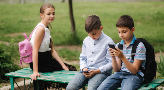 A girl looking at two boys on their phones.