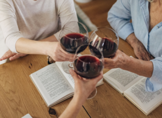 Women drinking wine and sharing a book.