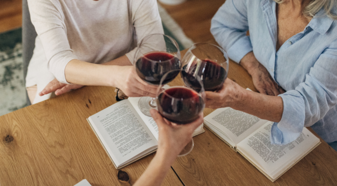 Women drinking wine and sharing a book.