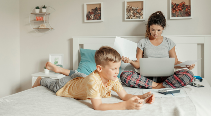 Decision Fatigue Is Ruining My Life A woman working on her computer with her son laying on her bed.