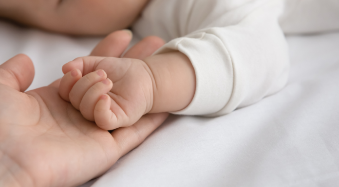 A moms handing holding a baby's hand.
