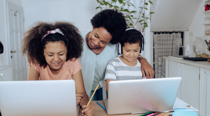 A mom homeschooling her children while they are on computers.