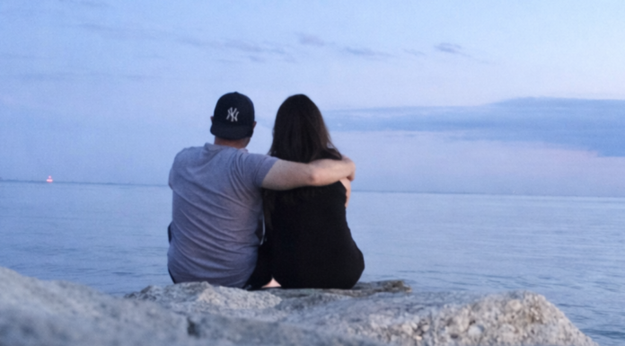 The Marriage You Start Isn’t the Marriage You Keep A couple sitting on the rocks at the beach watching the sunset.
