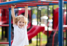 A boy hanging on the monkey bars.