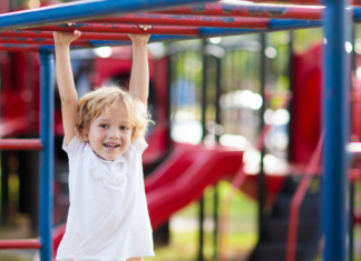 A boy hanging on the monkey bars.
