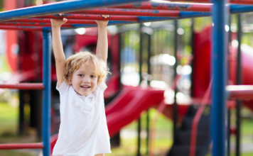 A boy hanging on the monkey bars.