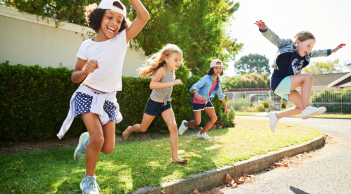 Kids playing outside and jumping off the curb.