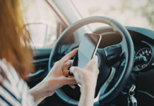 A woman on her phone sitting in her car.