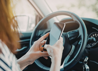 A woman on her phone sitting in her car.