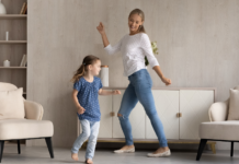 A mother dancing with her daughter in the living room.