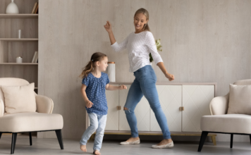 A mother dancing with her daughter in the living room.