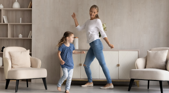 A mother dancing with her daughter in the living room.