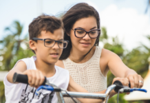 A mom helping her son ride a bike.