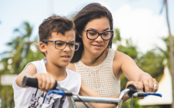 A mom helping her son ride a bike.