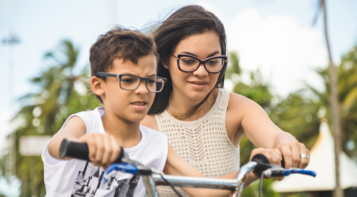 A mom helping her son ride a bike.