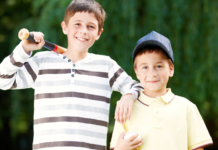 Boys holding a baseball and ball.