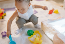 A girl playing in the sand with toys.