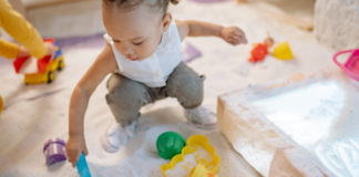 A girl playing in the sand with toys.