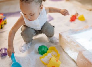 A girl playing in the sand with toys.