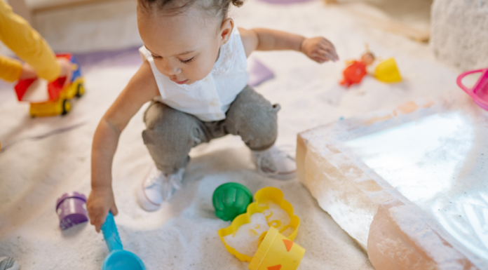 A girl playing in the sand with toys.