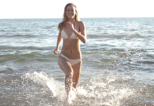 A woman wearing a bikini running in the water.
